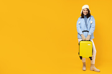 A woman in a warm ski suit with a suitcase.