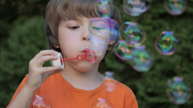 Little Boy Blowing Soap Bubbles Having Fun Playing Outside, Child Innocence and Curiosity. Boy Kid Blowing Soap Bubbles in Park, Garden and Nature, Having Fun, Joy and Childhood Development, Freedom.