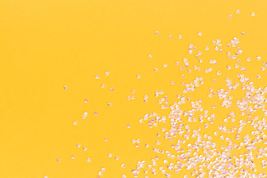 Silver crystal confetti scattered on a yellow background. Festive concept with copy space.