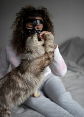woman giving treats to cat on sofa