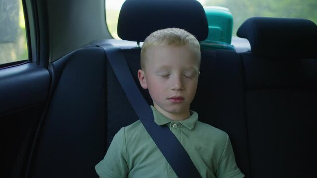 A boy sleeps in a child's car seat during a car ride with his parents. High quality 4k footage