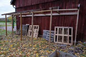Building firewood storage against red barn wall