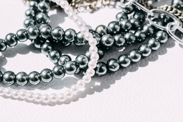 A necklace of gray beads with chain decorations on a white aesthetic background.
