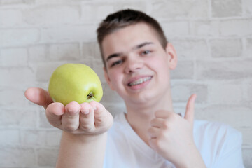 Teenager young man, European, close-up of braces on his teeth. Biting, holding a green natural apple. Concept of dental hygiene, prosthetics, permitted products for braces.