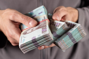 Man holds three bundles of hryvnia in her hand. Ukrainian money. Business concept. 1000 hryvnia...