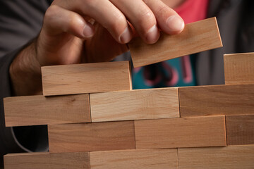 Man holding blocks wood game jenga Build wall. close up