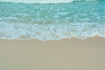 Fototapeta na wymiar Soft wave of blue ocean on sandy beach. Summer vacation in island. clear azure water Background.