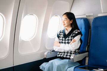 Attractive Asian female passenger of airplane sitting in comfortable seat while working laptop and tablet with mock up area using wireless connection. Travel in style, work with grace..