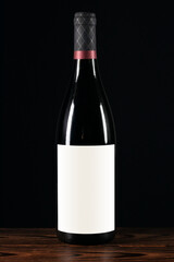 Red wine bottle with blank label on a wooden background