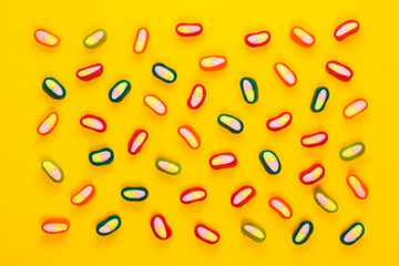 Fototapeta na wymiar Colorful gummy jelly candies on yellow background. Jelly sweets. top view
