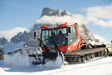 Piste groomer in front of the Dolomites alps Mountains, Italy. Snow groomer in dolomite alps in...