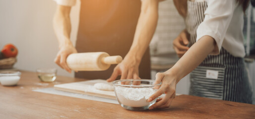 man in apron rolling out dough for homemade pastry, enjoying preparing biscuit cookies in modern...