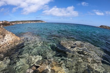Scenic view of a beach in Ibiza, with a sandy shoreline, blue sky, and turquoise waters