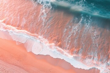 Aerial top view of a breaking wave on a beach with pink sand. Turquoise water with sea foam crushing on a beach