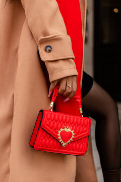 A woman holds a fashionable red handbag in her hands. Shopping in the big city