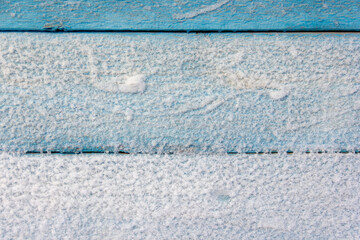 wall of old blue boards covered with snow background close-up texture