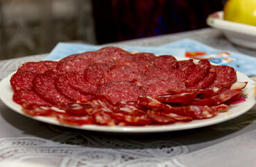 slicing smoked sausage on a plate on a festive table menu close-up