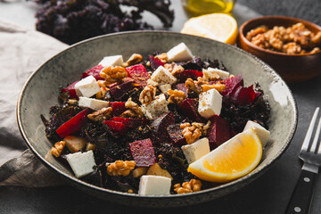 Salad of kale, roasted beets, walnuts and feta cheese on the table close up