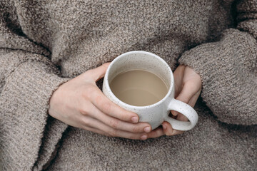 Winter, autumn cozy sbreakfast scene. Child, female hands in beige pullower holding blank white...