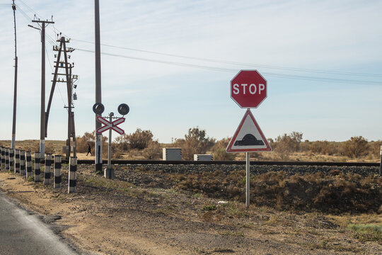 Aktau, Kazakhstan (Qazaqstan), 21.10.2023 - A railway crossing without a barrier. Road sign Stop and artificial hump.