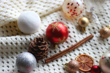 Various colorful Christmas ornaments, small presents and seasonal spices on white knitted blanket. Selective focus.