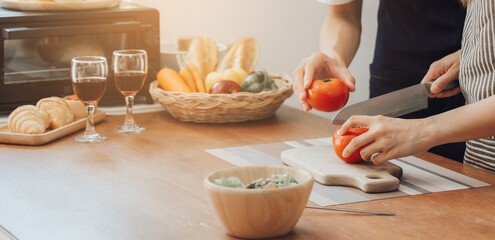 Unknown human hands cooking in kitchen. Woman slicing red tomatoes. Healthy meal, and vegetarian food concept