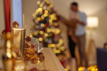 Christmas decorations while couple is decorating a tree in the background