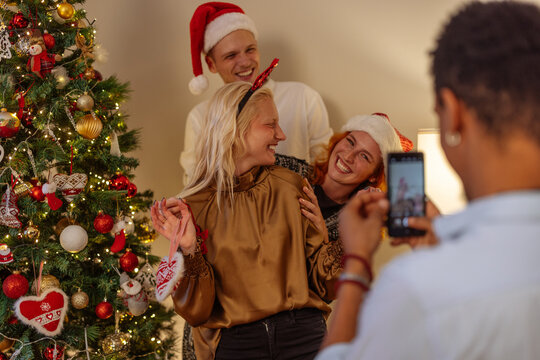 Three friends decorating a Christmas tree and posing for a picture