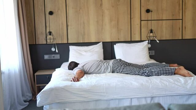 A man jumps onto a soft bed in the bedroom.