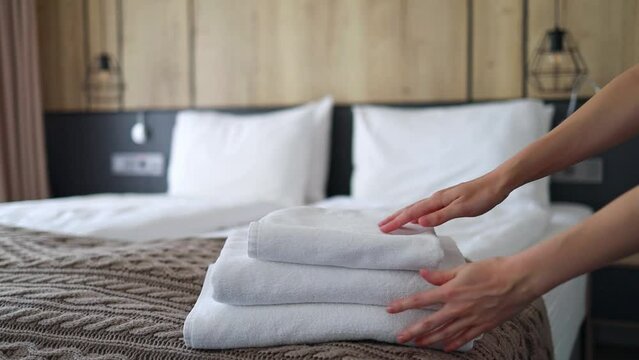 A woman puts fresh towels on the bed. Room service