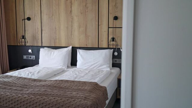 modern interior design with wood and gray decoration of a hotel bedroom with white linens and a brown blanket.