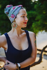 Portrait of a girl in a colored turban with red lips on a background of greenery and palm leaves