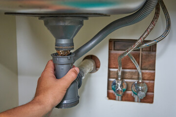 plumber cleans the siphon under the sink,Plumbing works to clean kitchen drains, care for plumbing...