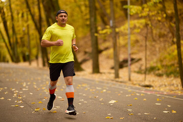 Obraz premium Portrait of a middle-aged man running in the park on an autumn day.