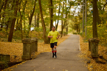Obraz premium Portrait of a middle-aged man running in the park on an autumn day.