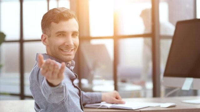 Young caucasian handsome man stretching hand at camera in greeting gesture.