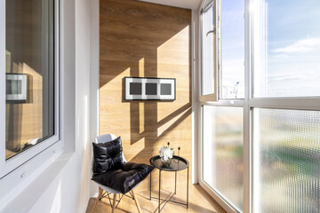 A small loggia in the apartment with a cozy armchair and a coffee table - obrazy, fototapety, plakaty