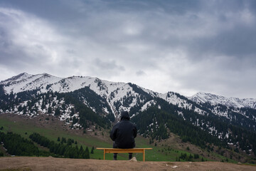 A man sitting on a bench in the mountains