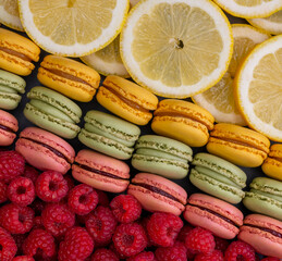 macaroons of different colors with raspberries and lemon