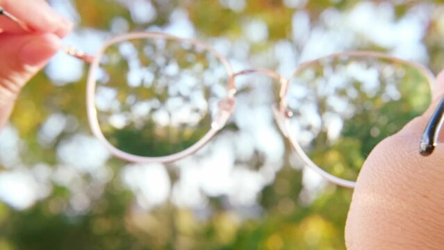 glasses with dirty lenses in female hands, individuals with poor vision adapt lifestyle choices and habits accommodate visual needs, Eyeglass Fashion
