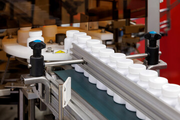 white plastic bottle moving on conveyor belt of auto capping and labeling machine at cosmetic,...