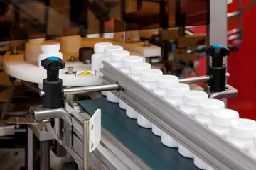Foto op Canvas white plastic bottle moving on conveyor belt of auto capping and labeling machine at cosmetic, supplement or medicine pharmaceutical manufacturing. © gumpapa