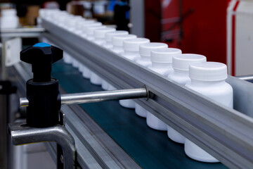 white plastic bottle moving on conveyor belt of auto capping and labeling machine at cosmetic,...
