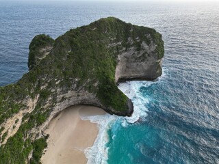 Drone aerial view of famous dinosaur (T-rex) shaped rock in turquoise waters splashing around it....