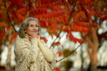 Senior woman walking in the park in autumn. 