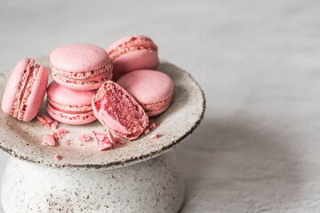 Fototapeta premium Traditional French macaroons. Pink almond cookies on a stylish ceramic plate on a gray stone background. Delicious dessert.