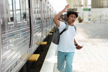 Young asian man tourist with backpack running by train station