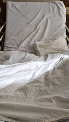 Fototapeta na wymiar 皺になった介護ベッドのシーツと窓から注ぐ朝の太陽光