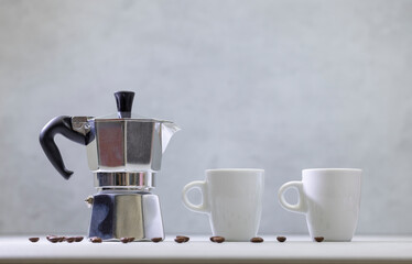 Metal geyser coffee maker on table with cup