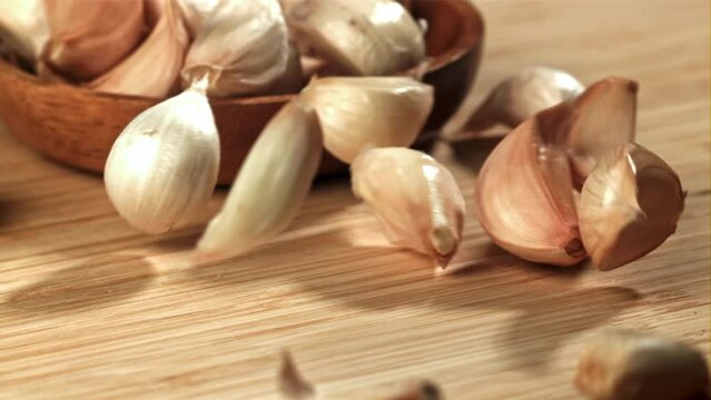 Fresh garlic falls on a cutting board. Filmed on a high-speed camera at 1000 fps. High quality FullHD footage